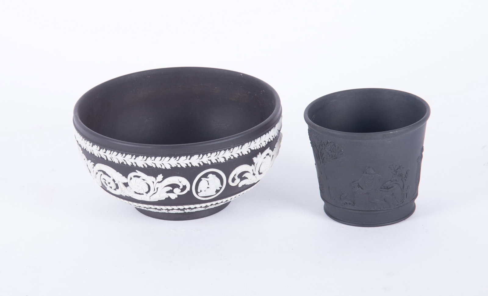 A Wedgwood Black Jasper Arabesque Bowl and Antique Basalt Vase: England, a Wedgwood Black and White jasperware bowl in the Arabesque pattern with sinuous vines and classical figures, date mark for 1967. Paired with a 19th century Wedgwood (only) small jardiniere