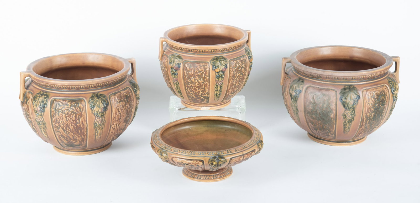 A Collection of Roseville Florentine Art Pottery: Zanesville, circa 1925, having a wide-round body with grape and vine textured panels in shades of brown and green, the lot includes 2 larger jardiniere, a mid-size jardiniere (chip at base) and