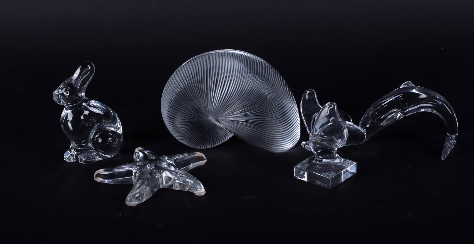 A Collection of Five Baccarat Crystal Table Articles: France, late 20th century, a large clear and frosted crystal Nautilus Shell, a Star Fish, a Butterfly, a Rabbit (Neiman-Marcus edition), and a Dolphin. All marked Baccarat.