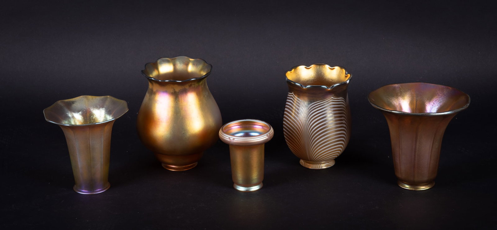 Five Antique Gold Aurene Lamp Shades: Five Antique Gold Aurene Lamp Shades American, a large unsigned gold aurene shade (6 3/8 inches tall, 2 1/4 inch outer fitter lip); an unsigned pulled leaf design shade (5 7/8 inches tall, 2 1/8 inch