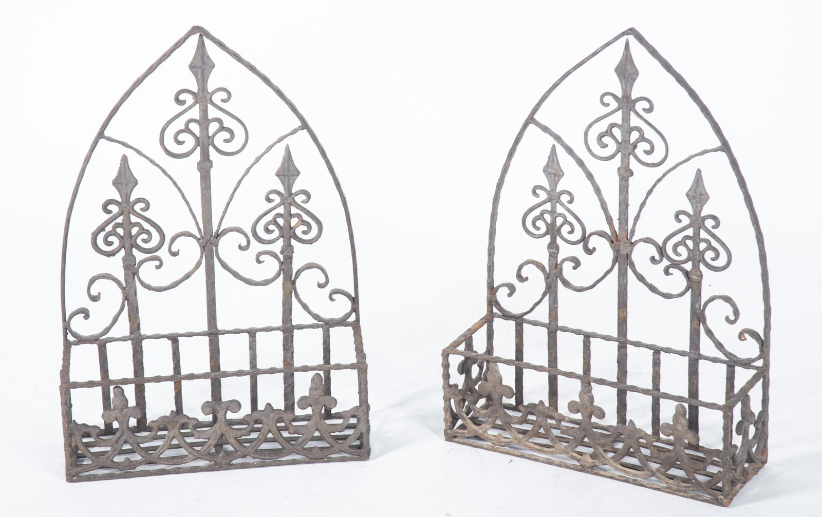 Pair of Wrought Iron Wall Shelf Basket Planters: Pair of Wrought Iron Wall Shelf Basket Planters Arched panel design features stylized fleur de lis accents. Basket measures 5 x 14 x 4 inches. 21 x 15 x 5 1/4 inches (overall)