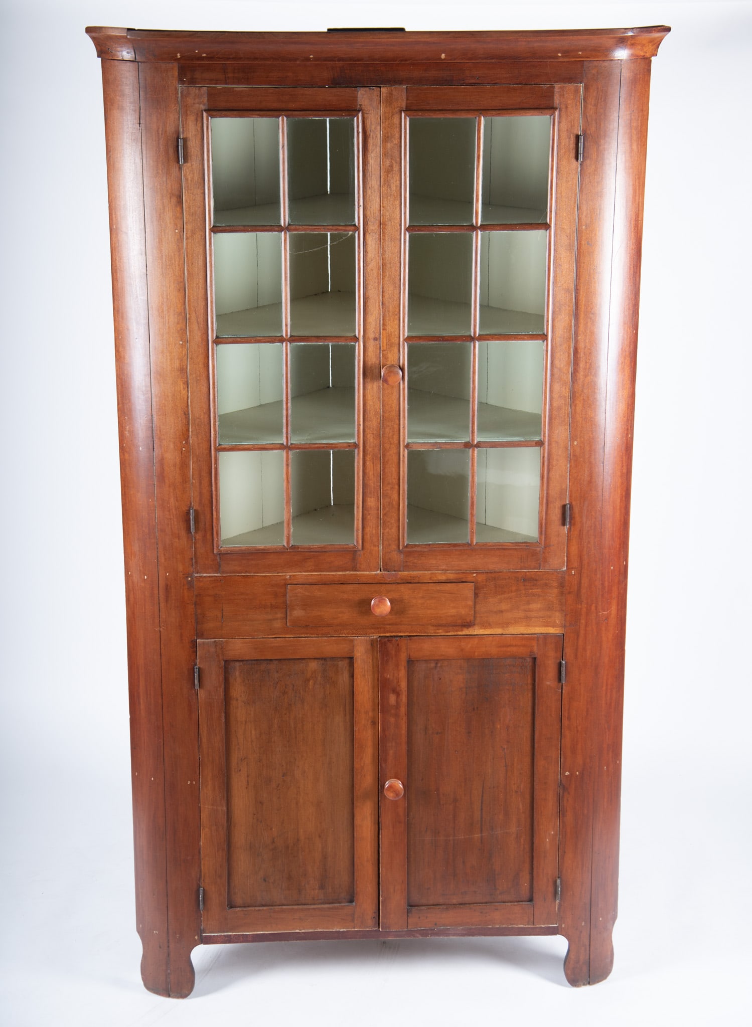 Nineteenth Century American Corner Cupboard: Nineteenth Century American Corner Cupboard Shaped cornice above a pair of doors each with eight individual glass panels and a single drawer with a pair of hinged inset panel doors below ending on sha