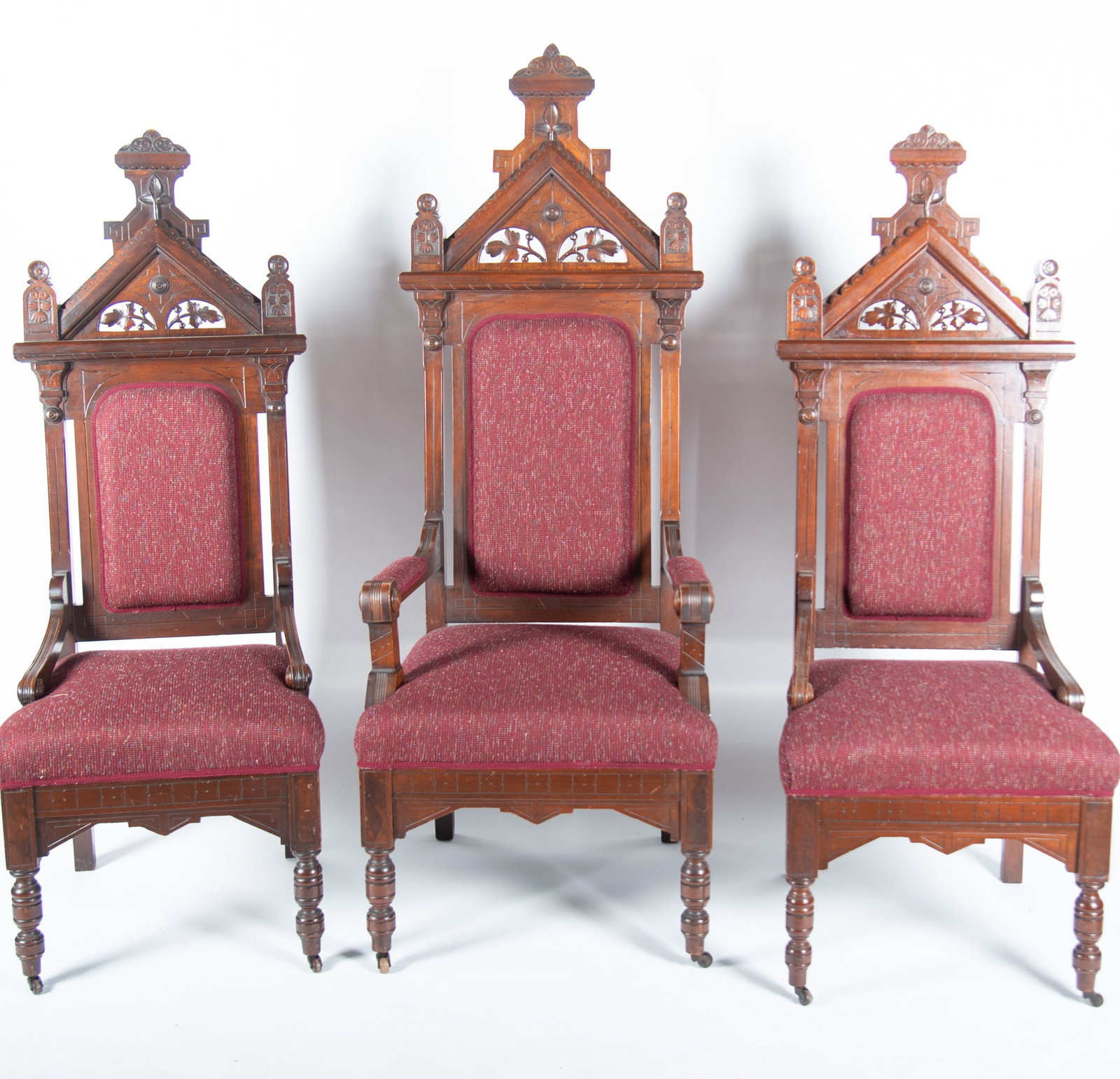Pair Of Early Twentieth Century Gothic Throne Chairs With Matching Armchair (3 pieces): Pair Of Early Twentieth Century Gothic Throne Chairs With Matching Armchair (3 pieces) The carved floral and pediment design crest above burgundy upholstered and padded back and seats ending on turned