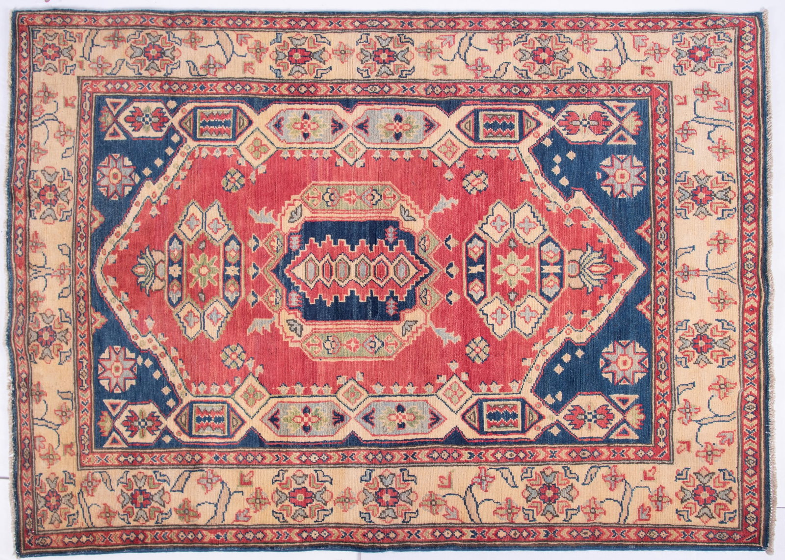 Handwoven Kazak Area Rug: Handwoven Kazak Area Rug Central shaped elongated medallion within a shaped border on a salmon field with blue spandrels and a wide floral primary border and a pair of guard border. 4' 3" x 5' 9"