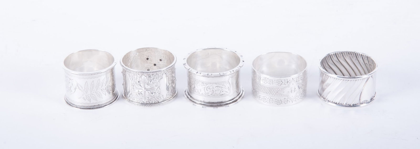 Five English Sterling Silver Napkin Rings: Five English Sterling Silver Napkin Rings England, an assortment of 5 vintage and antique sterling silver napkin rings, most with botanical details. 4.87 total troy ounces Widest: 1 1/4 inches