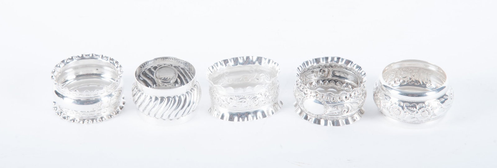 Five English Sterling Silver Napkin Rings: Five English Sterling Silver Napkin Rings England, an assortment of 5 vintage and antique sterling silver napkin rings, some with flared rims and botanical details. 3.03 total troy ounces Widest: 1 in