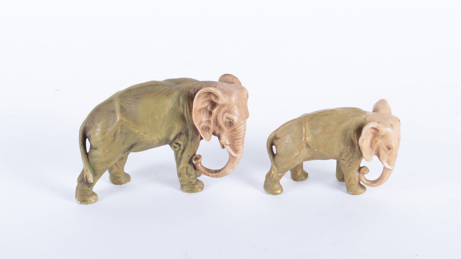 Two Royal Dux Style Porcelain Elephants: Two Royal Dux Style Porcelain Elephants Bohemia, early 20th century, a female and calf elephant, both in the typical Royal Dux shades of brown and green with gilt highlights. Numerical marks to unders