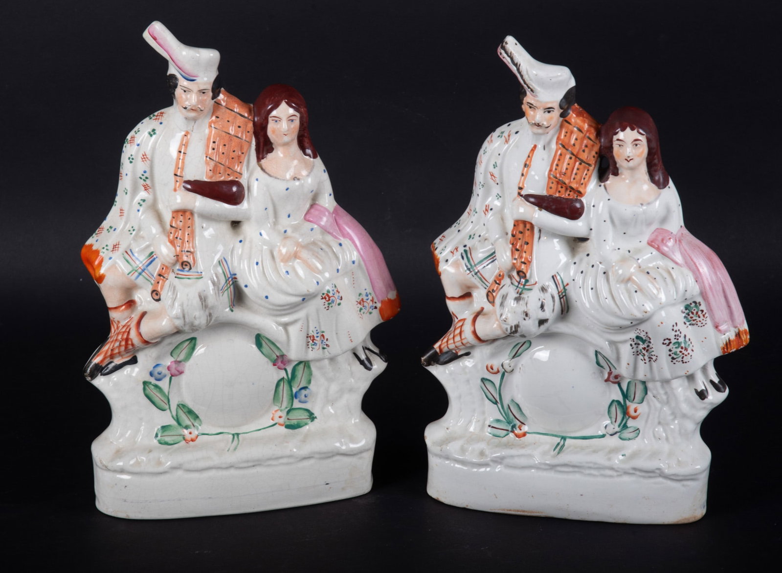 A Pair of Antique Staffordshire Figure Groups, Scottish Highlander Couple: A Pair of Antique Staffordshire Figure Groups, Scottish Highlander Couple England, circa 1870, two Staffordshire pottery groups of a Highlander lad and lass perched on a clock. 8 x 13 3/8 inches