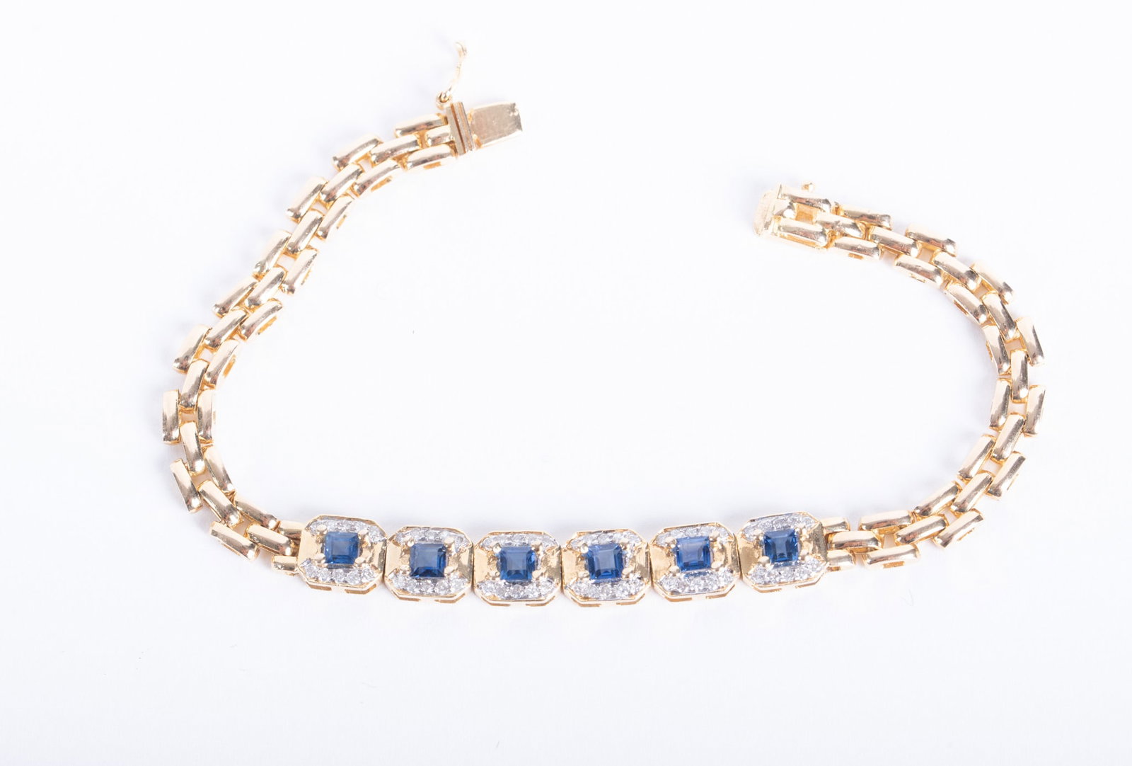 14K Yellow Gold Sapphire Diamond Bracelet: 14K Yellow Gold Sapphire Diamond Bracelet This unusual bracelet has a row of six emerald cut sapphires, each surrounded by a halo of diamonds. A double link chain on either side completes this 7 inch 