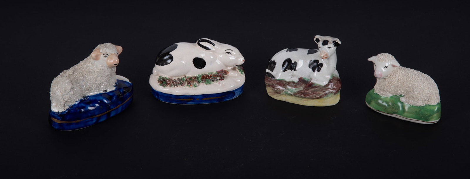 Four Antique Staffordshire Animals: Four Antique Staffordshire Animals England, 19th century, the lot consists of a rabbit, spotted cow, a recumbent sheep on blue base, and a recumbent sheep on green base. Largest: 2 3/4 x 3 3/8 inches
