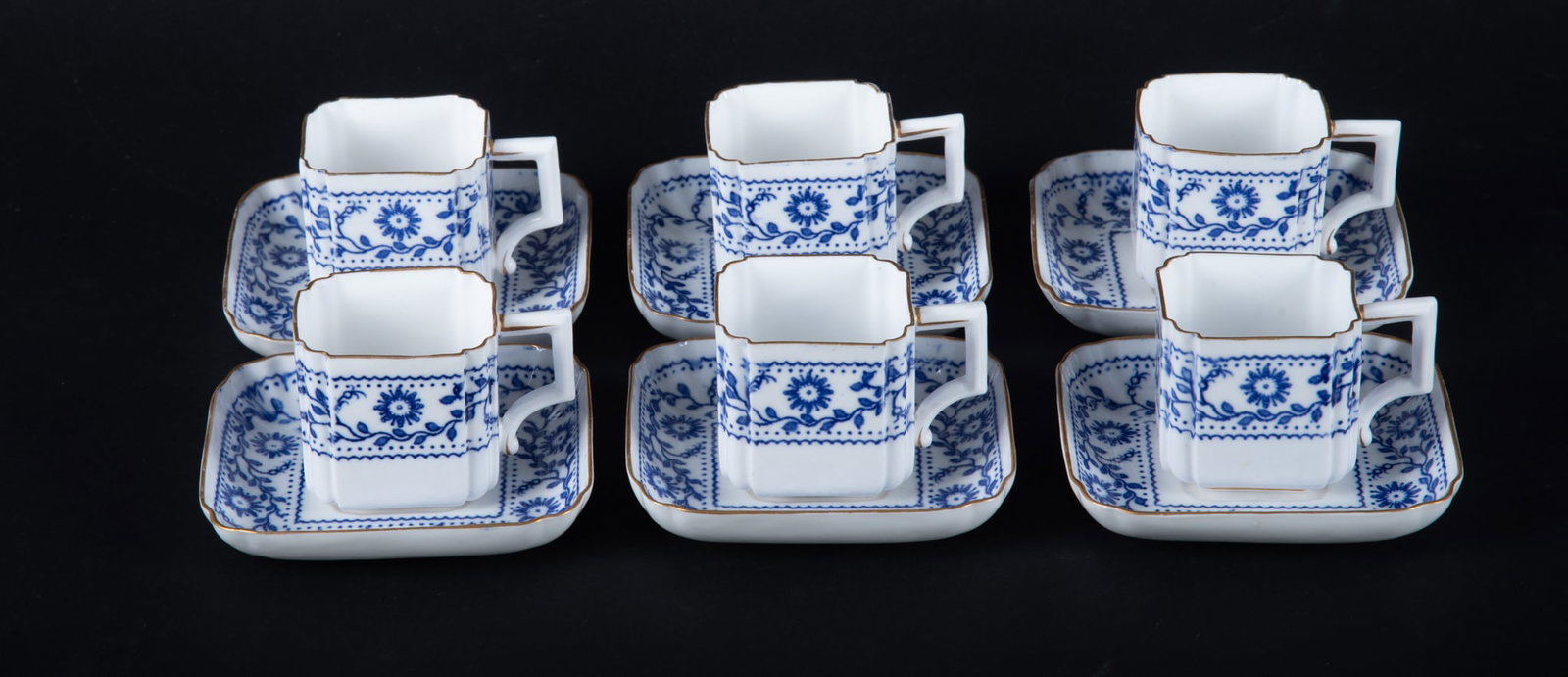 Six Crown Derby Porcelain Demitasse Cups and Saucers: Six Crown Derby Porcelain Demitasse Cups and Saucers England, circa 1880, the set of 6 in a very unusual rectangular shape with borders of blue botanicals on a white ground. Gilt highlighting.