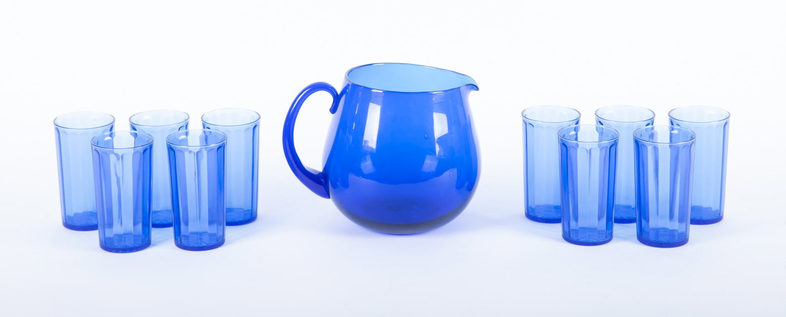 An Art Deco Style Water or Lemonade Set: An Art Deco Style Water or Lemonade Set A blown glass pitcher of deep cobalt, paired with 10 panel-pattern cobalt blue glasses. Picher: 7 x 8 1/2 inches; Tumblers: 4 3/4 inches tall