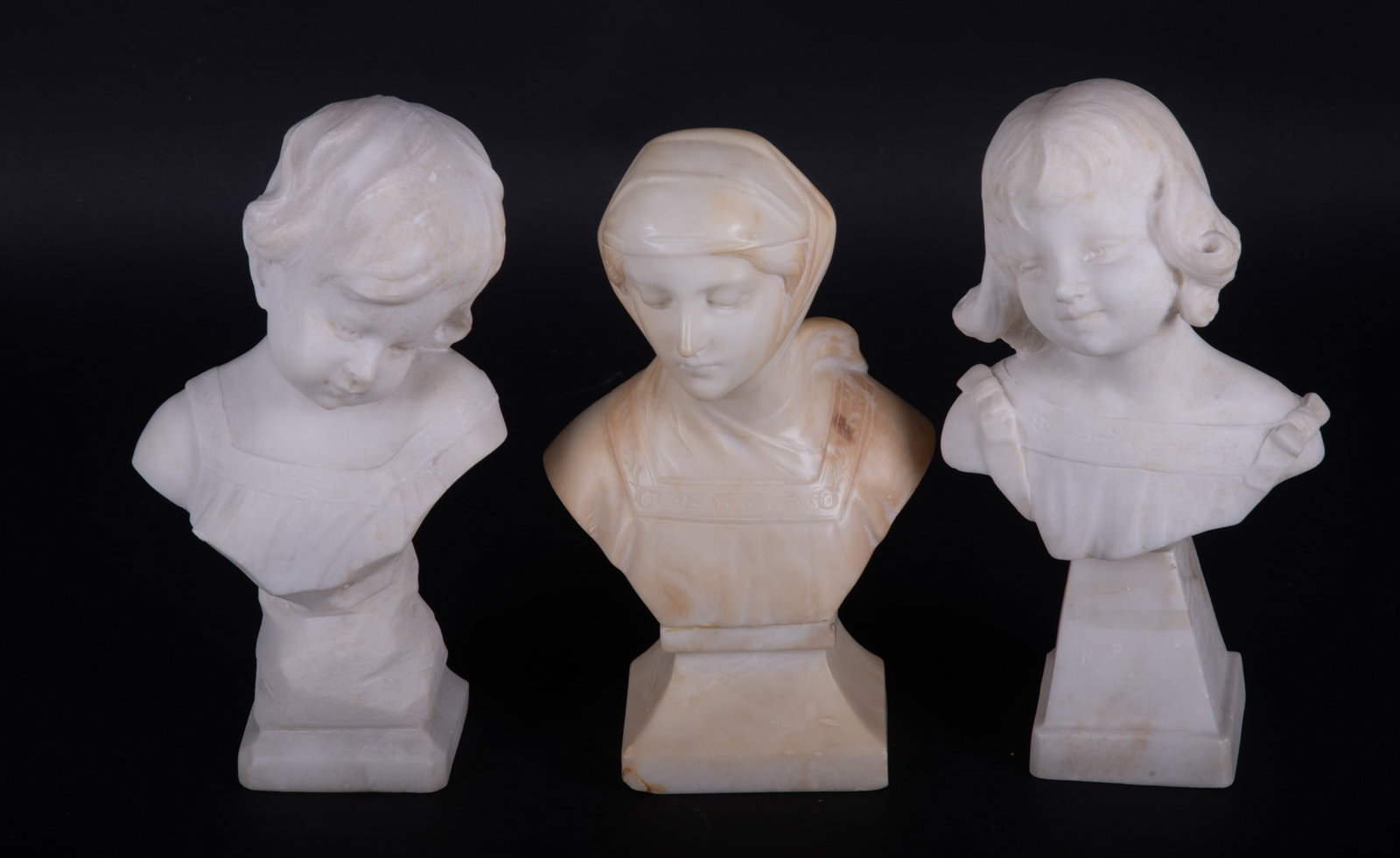 Antique Carved Marble Busts: Antique Carved Marble Busts The lady with the scarf has a mottled surface in cream to beige colors. She is 9 3/4 inches tall and has a chip on her plinth. The precious little girl bust is carved in