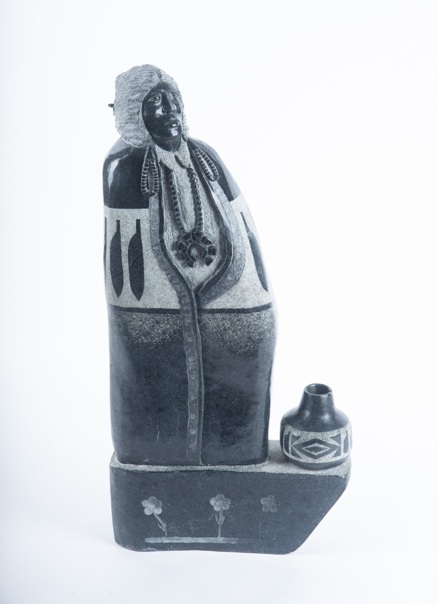 Navajo Carved Stone Figure: Navajo Carved Stone Figure Carved figure of a Native American woman, standing beside a piece of pottery. 22 x 10 1/2 x 3 inches