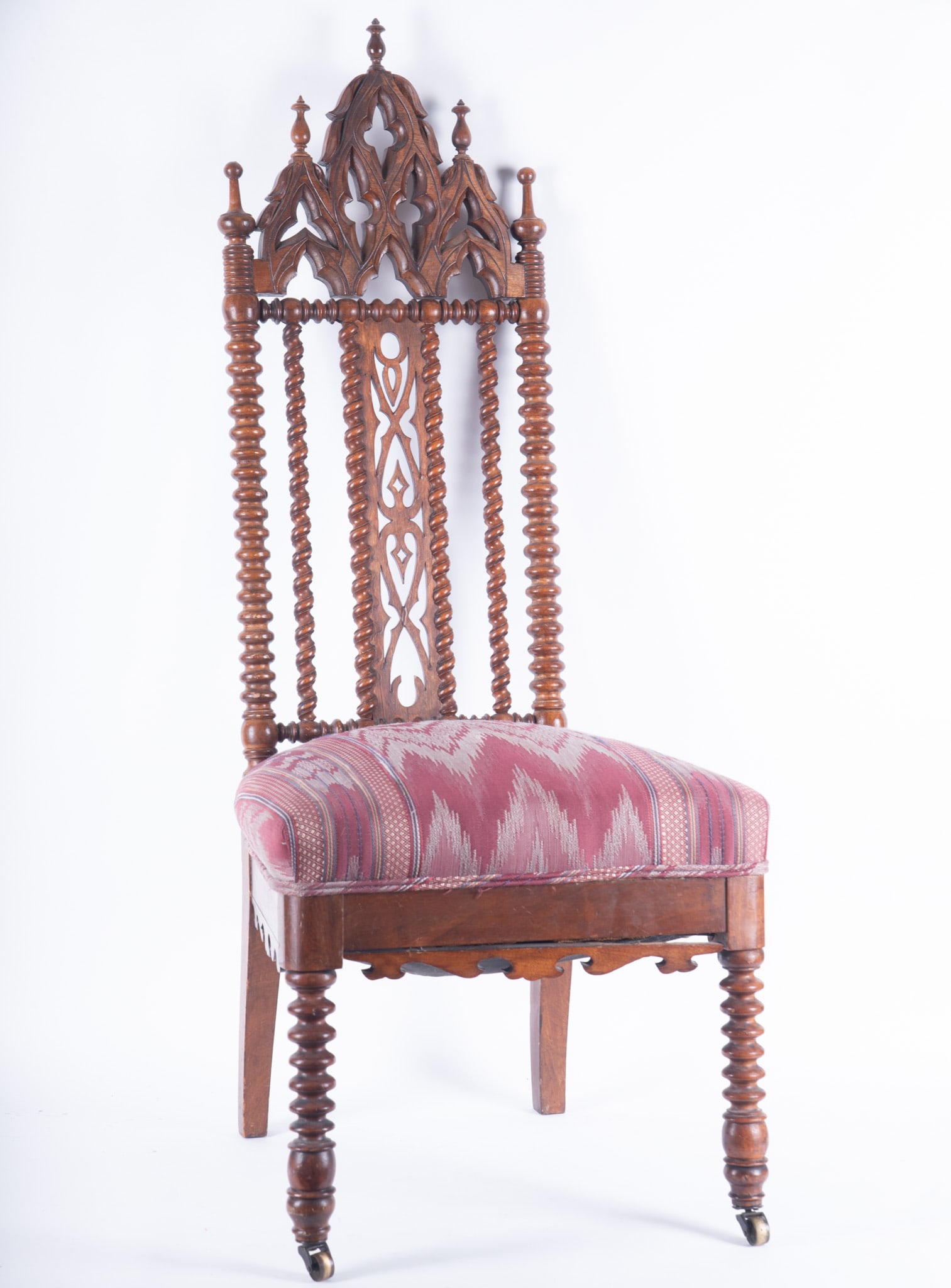 19th Century Victorian Gothic Revival Chair: 19th Century Victorian Gothic Revival Chair 19th Century side chair features bobbin-turned legs and side posts with an elaborate pierced carved spire crest back with updated upholstery. Casters. Back 