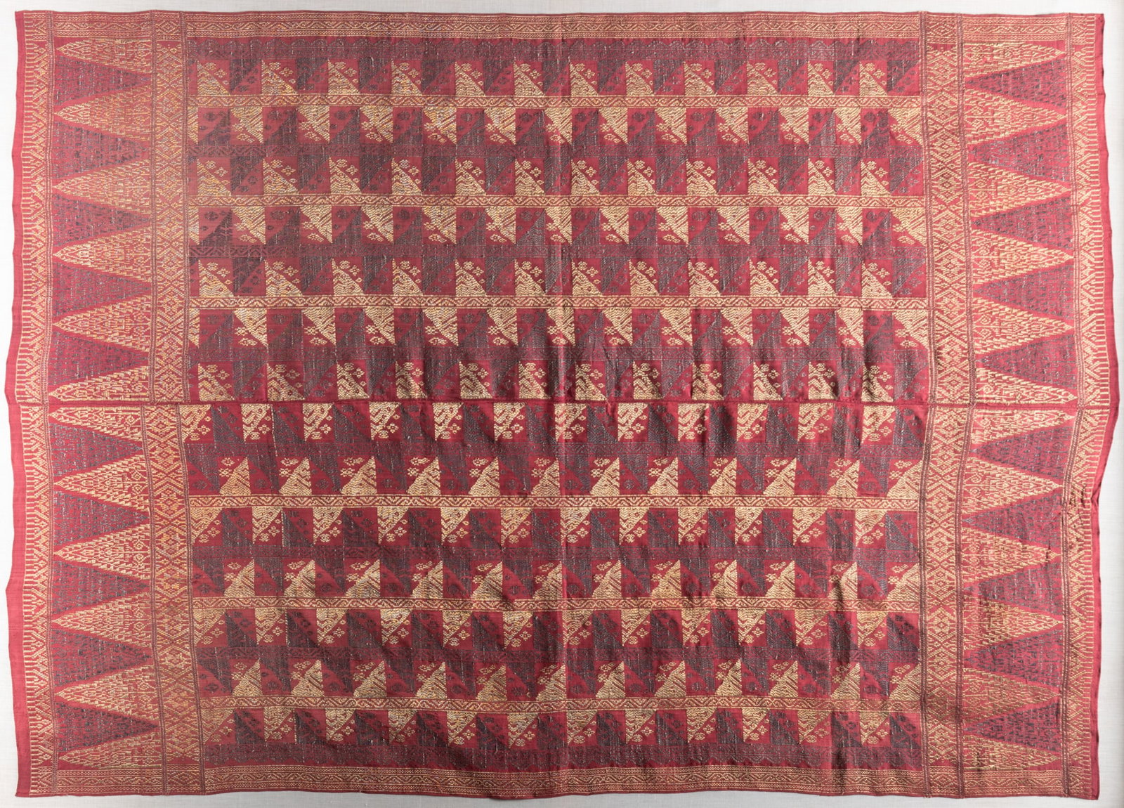 A Framed Tibetan Textile: A Framed Tibetan Textile Finely woven with gold and silk threads, a repetitive geometric pattern on a red ground, framed. 46 1/2 x 64 1/2 inches; 53 x 71 1/2 inches (overall with frame)