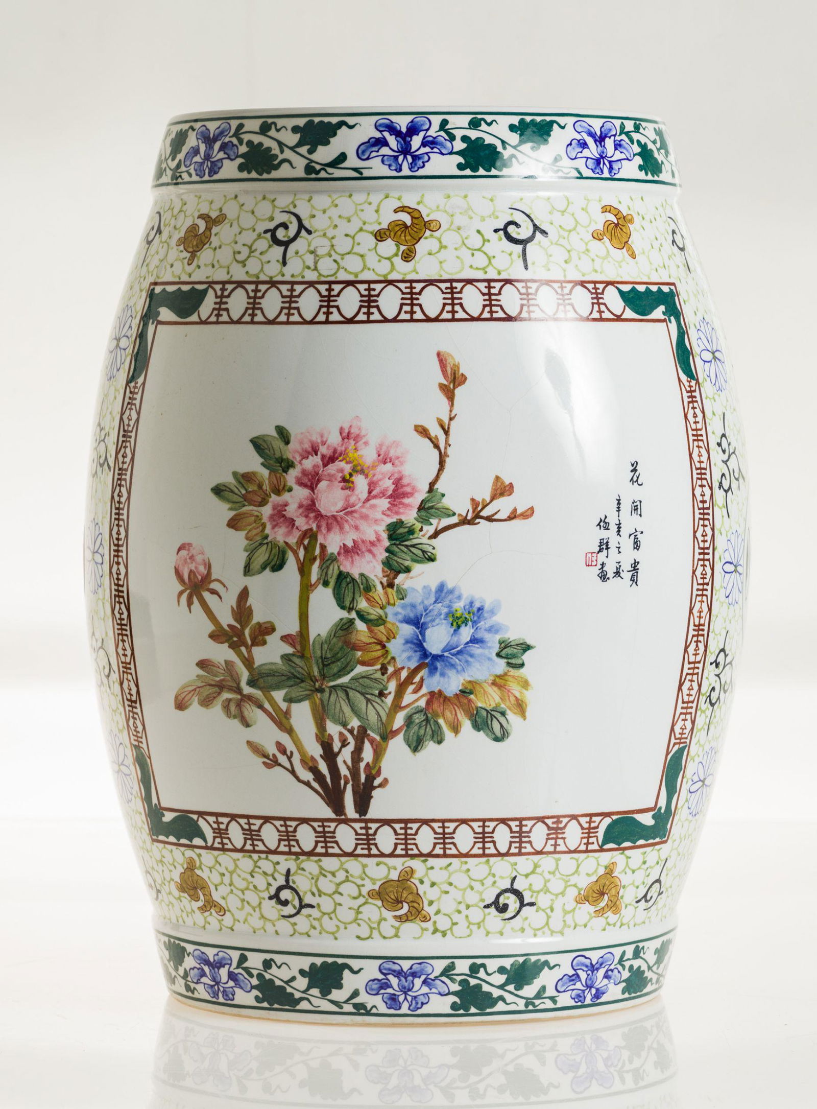 Enameled earthenware stool, China, 20th century: With pink and blue flower decoration on one side and Chinese sinogram on the other. With a fretwork of green and blue flowers at the base and mouth. Measurements: 45 x 26 cm