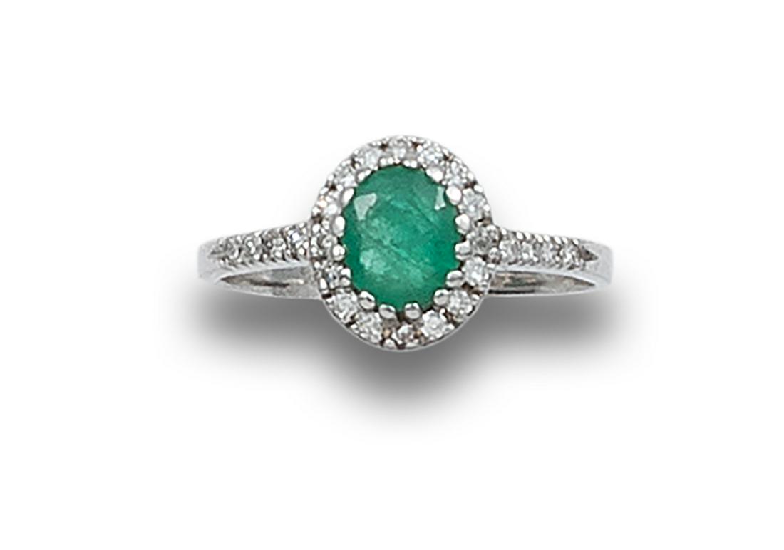 EMERALD ROSETTE RING, DIAMONDS, WHITE GOLD: Rosette ring in 18 kt white gold. Formed by a central emerald, oval cut, estimated at 0.60 ct. edged with diamonds, brilliant cut. Setting in claws and in grain.