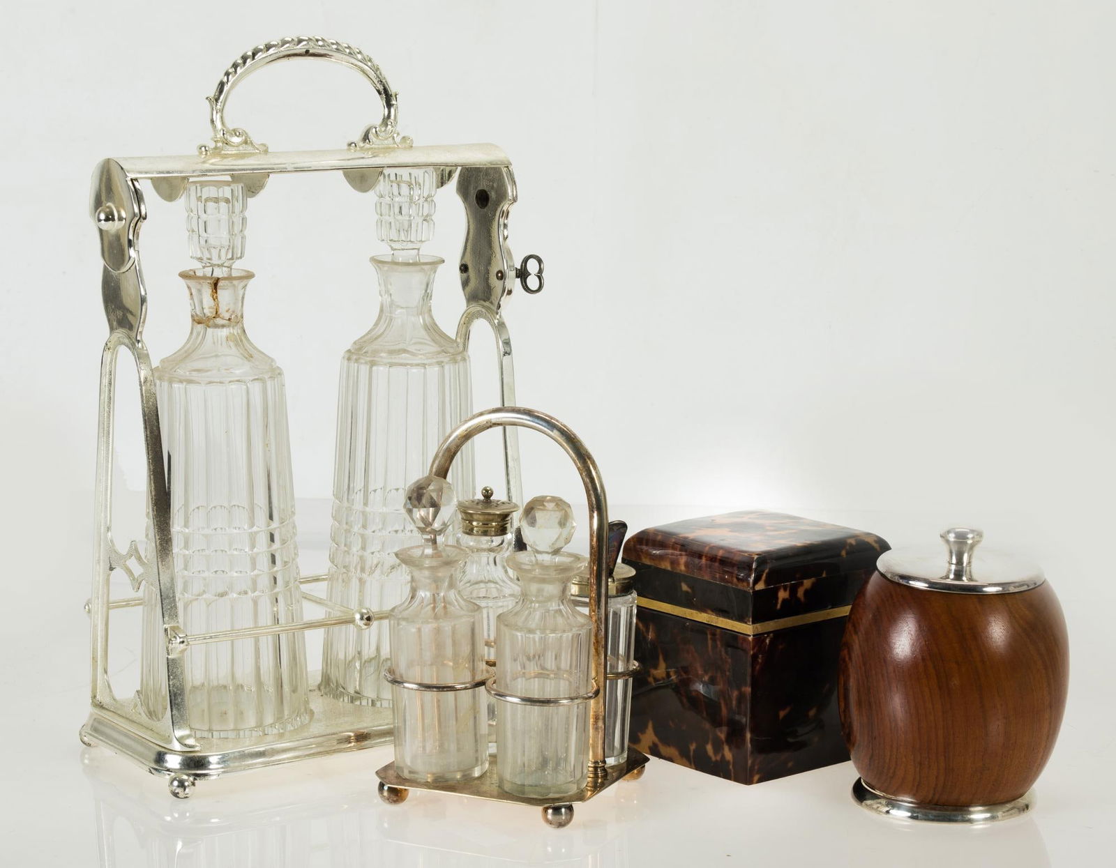 Lot consisting of metal tantalus with two flasks, cruets and two tobacco boxes, 20th century: One of the boxes with a wooden core and an exterior simulating tortoiseshell. The jars and cruets with marks, hair and defects and one of the tobacco boxes with the base detached. Measurements: 38 cm,