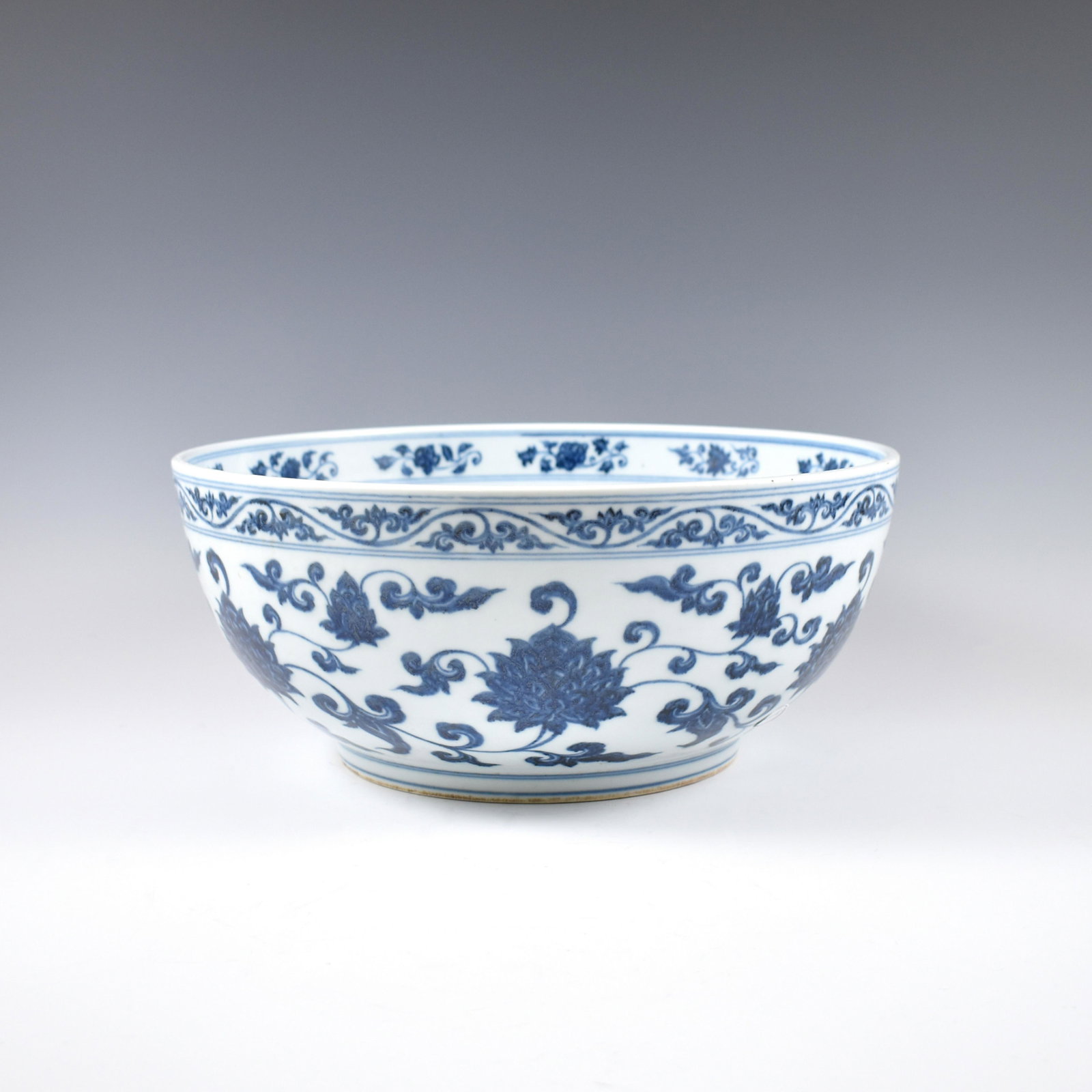 MING BLUE & WHITE SCROLLING FLORAL BOWL: Dimensions: 6-1/4" H x 14-1/4" Dia. Chinese Ming Dynasty Period, blue and white bowl. The porcelain potted with a shallow body, slight deep, broad cavetto, with a straight opening lip, raised on a sma