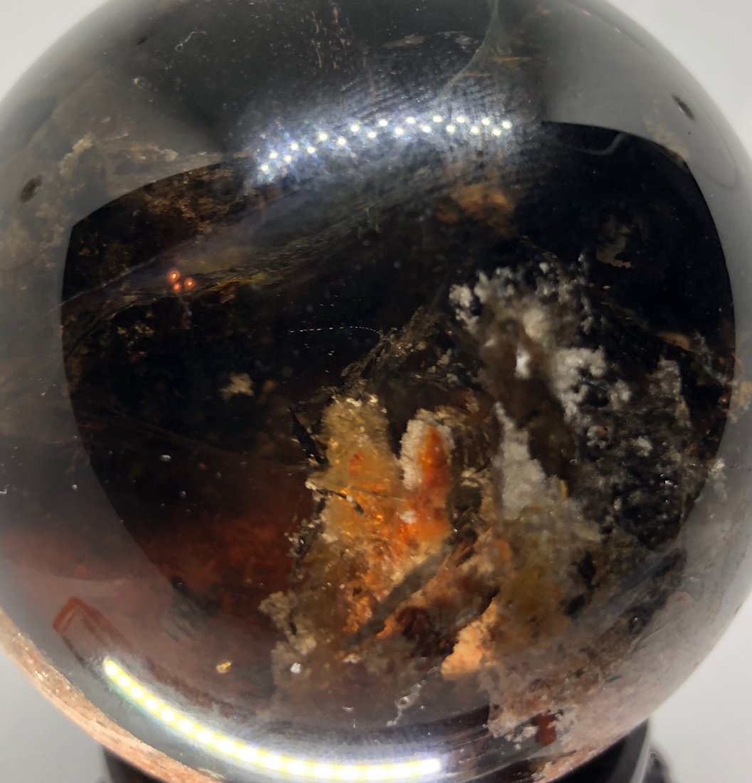 Dark Smokey Garden Quartz Sphere: Amazing dark smokey colored garden sphere with shades of red. Great alien landscape in this sphere. Must see to appreciate. Approx 3" diameter. 430 grams. Comes with stand as pictured. AS ALWAYS WE OF