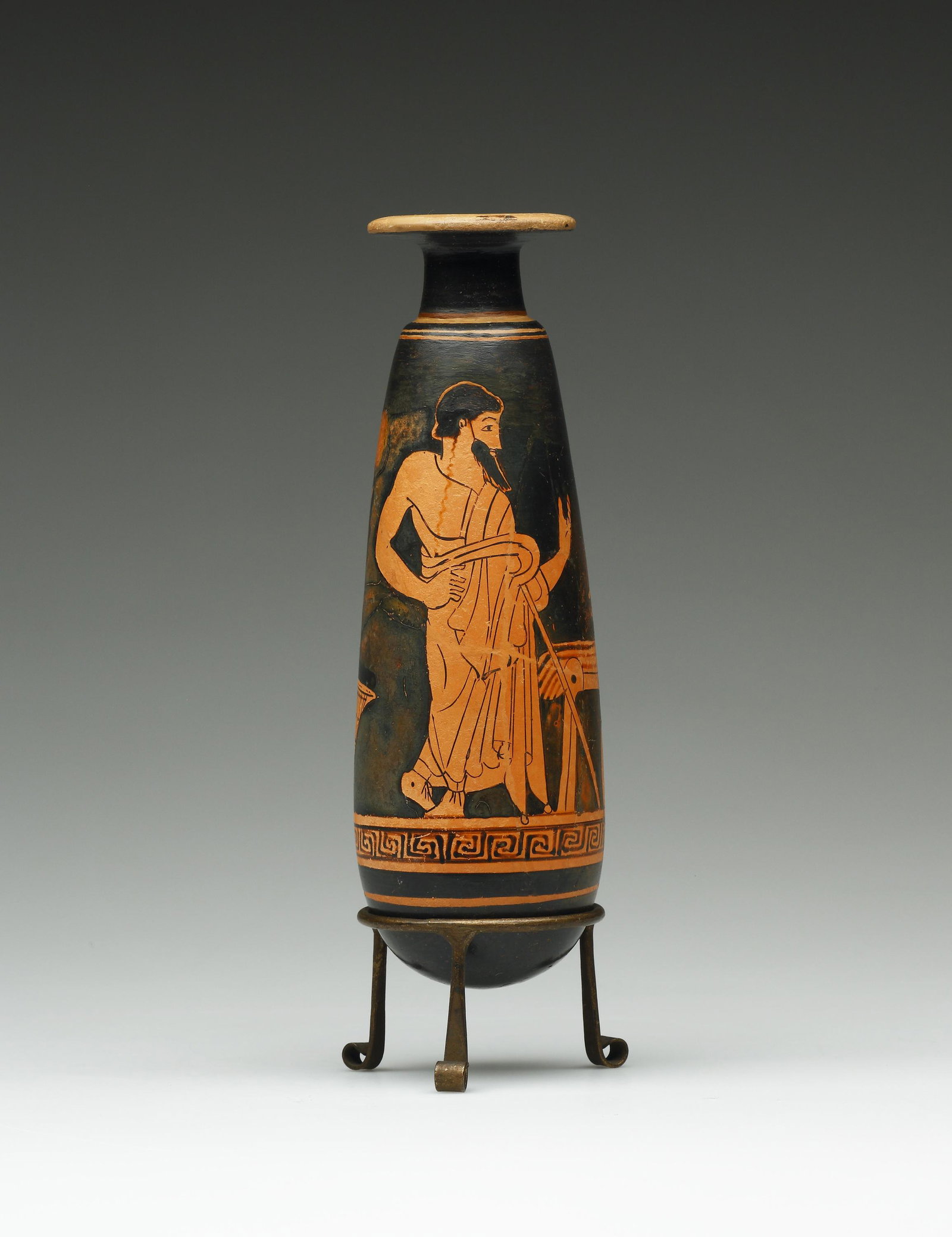 A Red-figure Alabastron: Attic 500-450 B.C.. Terracotta. H. 18 cm Attributed to the Painter of Munich 2676. A man in a himation stands with his body facing the beholder but his head turned to right. He leans on the staff on h