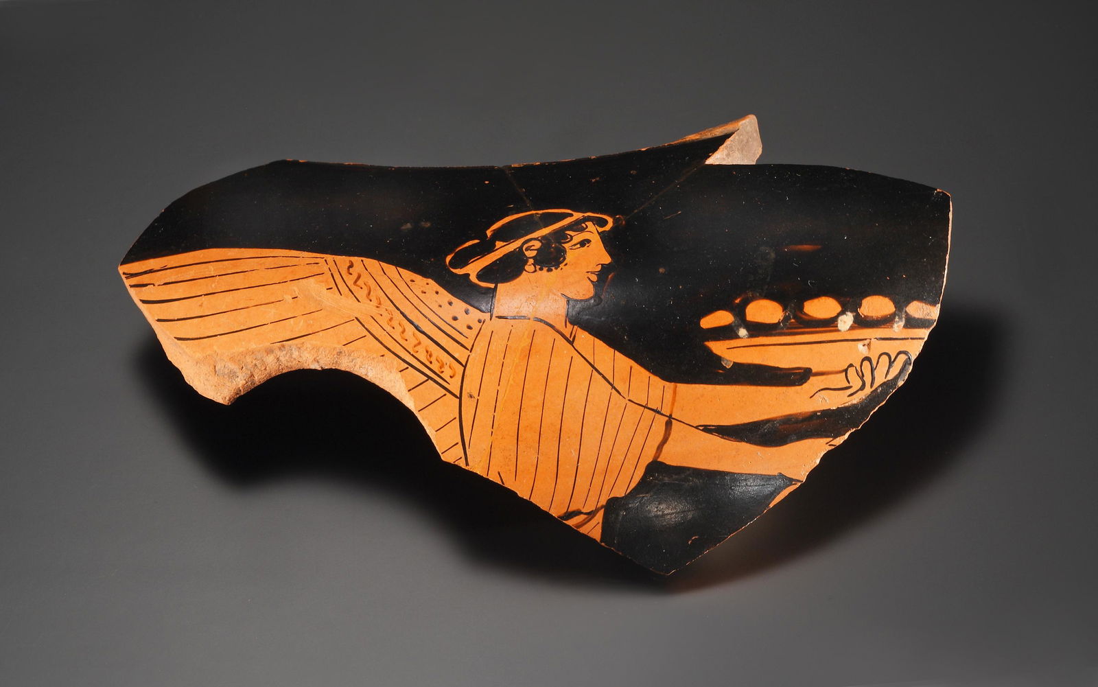 A Fragment of a Red-figure Column-krater: Attic ca. 470-460 B.C.. Clay. W. 14,5 cm Attributed to the Syracuse Painter. On this fragment, from the shoulder of a small column-krater with unframed pictures, the upper part is preserved of Nike in