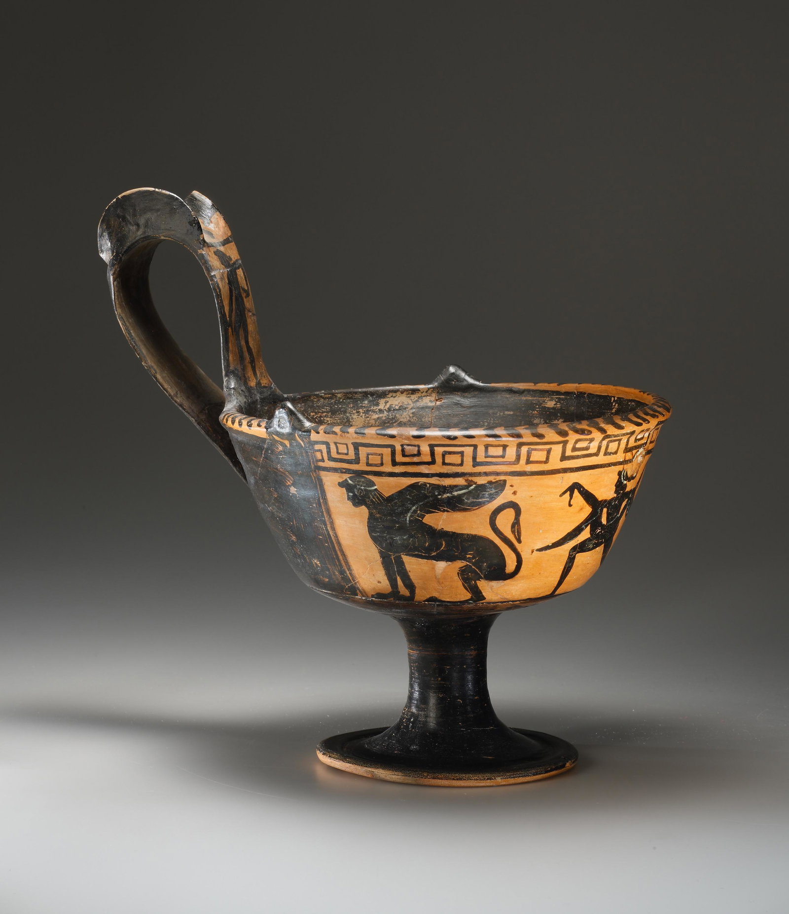 An Etruscan Black-Figure Kyathos with Sphinx and Dancer: Etruscan ca. 525-500 B.C. Clay. H. (including handle): 26.6 cm. Attributed to the Micali Painter. A panel of reserve dominates the cup's exterior. At its center a male dancer progresses towards the le