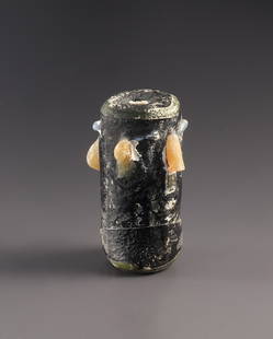 A Glass Bead with Double Face: East or South Mediterranean, Phoenician or Punic 4th - 2nd cent. B.C..Opaque black, yellow, and green glass. H. 2.7 cmCylindrical head with horizontal and vertical tips of yellow and gray glass