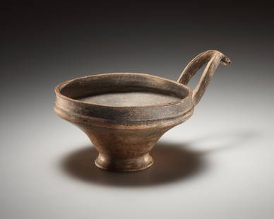 A One-handled Cup (Base Ring Ware): Eastern Mediterranean, Late Bronze Age 1475-1225 B.C..Clay. Dm. 12.8 cmLow, slightly flared foot moulded out of the wide, conical bowl. S-shaped stirrup handle attached to shoulder with semi-circular