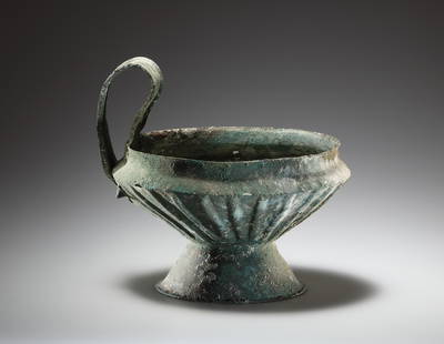 A Rare Kyathos in Bronze: Italic early 7th cent. B.C..Bronze. H. 17.1 cm at handle; diam. of rim 16.2 cm. Large kyathos (dipping vessel) wrought in three parts of hammered bronze. The flaring, ribbed body has offset, everted