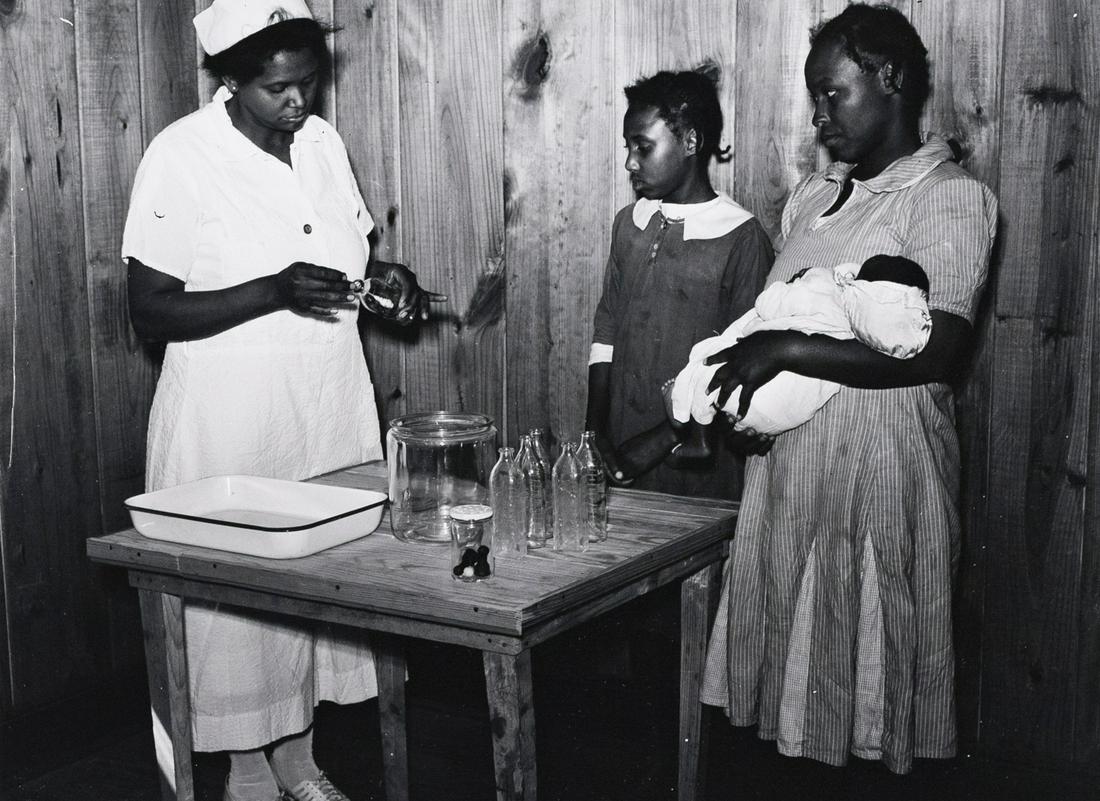 MARION POST WOLCOTT Nurse & Mothers Alabama 1939: MARION POST WOLCOTT, Nurse Shamburg demonstrates care of baby bottles to Mrs. Paralee Coleman and Marie. Mothers have to work in field and children are left at home to care for babies. Health clinic,