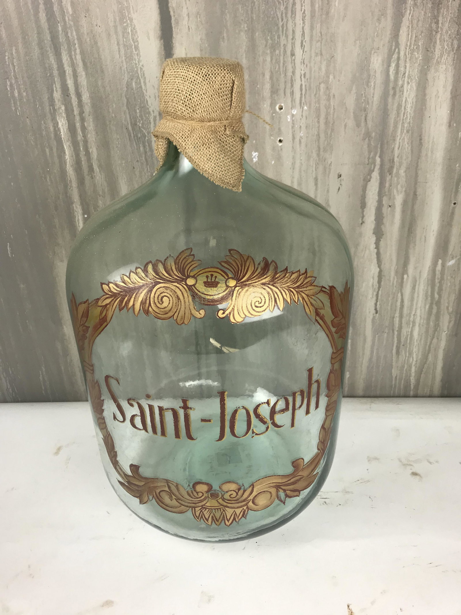 Painted Wine Bottle With Burlap Top: Stunning wine bottle painted with the name "Saint-Joseph" and adorned with a burlap top