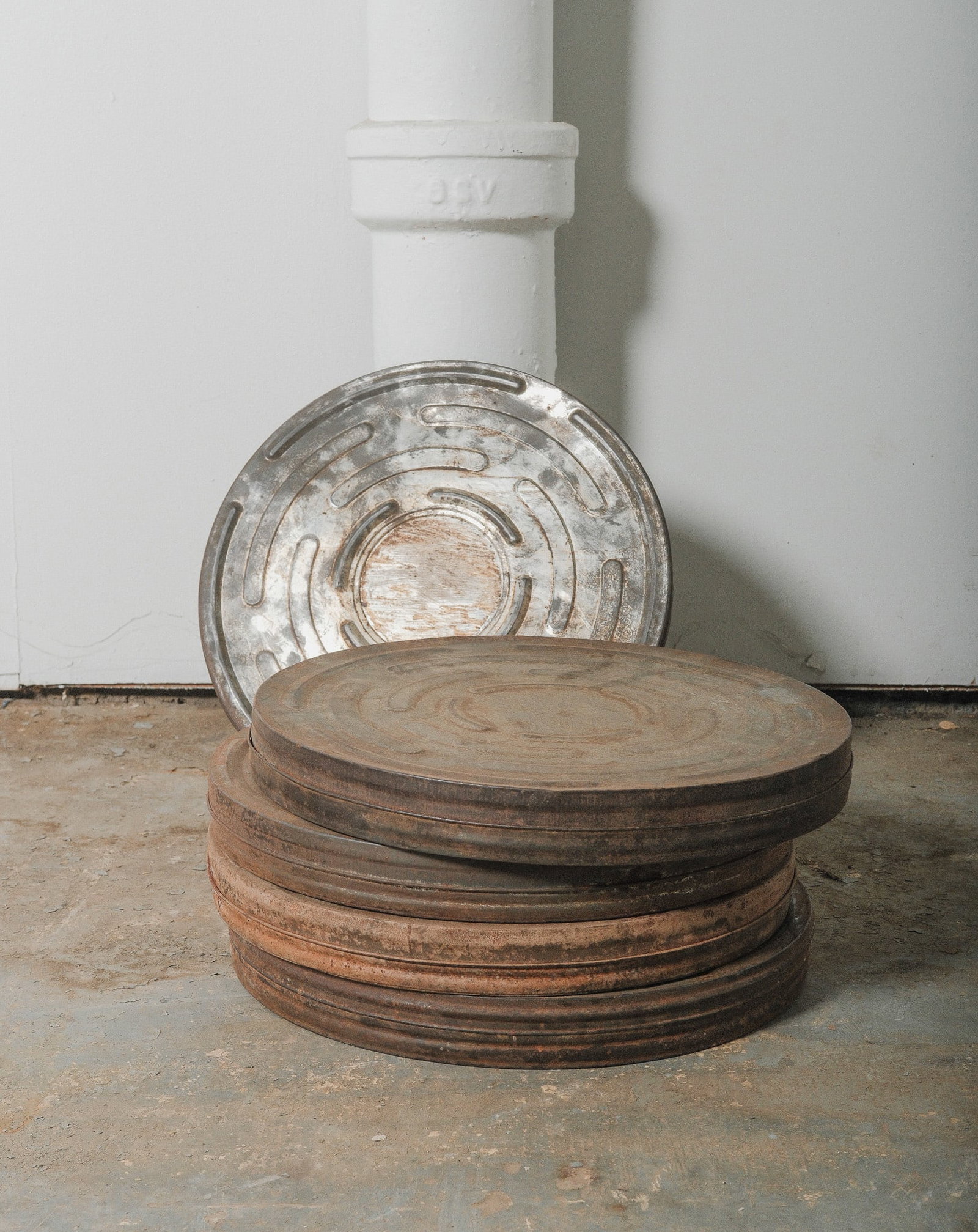 Set of 5 Vintage Industrial Film Reel Canisters with original weathered patina: Stack of vintage industrial film canisters, each bearing rich, rusted textures and classic concentric design. Originally used for housing motion picture reels, these metal tins now make striking decor