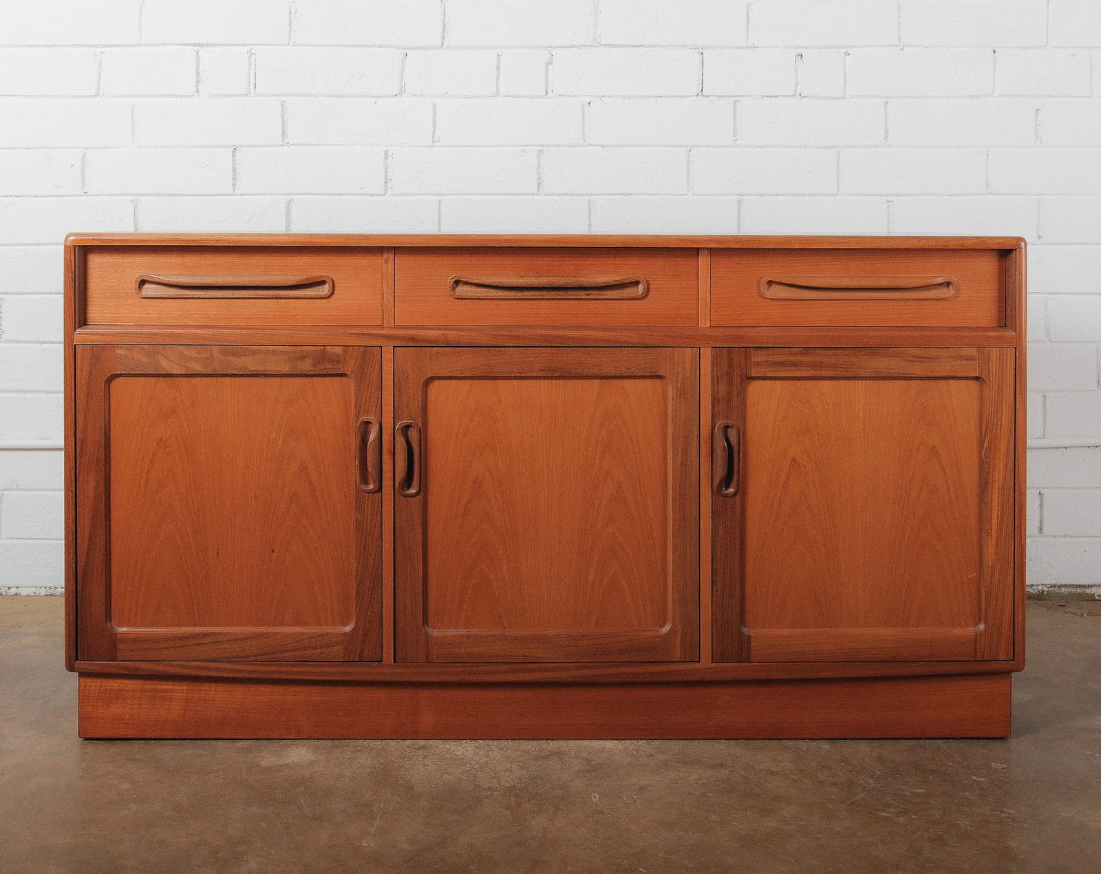Mid-Century Modern Credenza/Sideboard with Drawers: A functional mid century modern credenza featuring two upper drawers above a double door cabinet. The piece rests on a plinth base and features recessed pulls, offering a clean-lined, practical storag