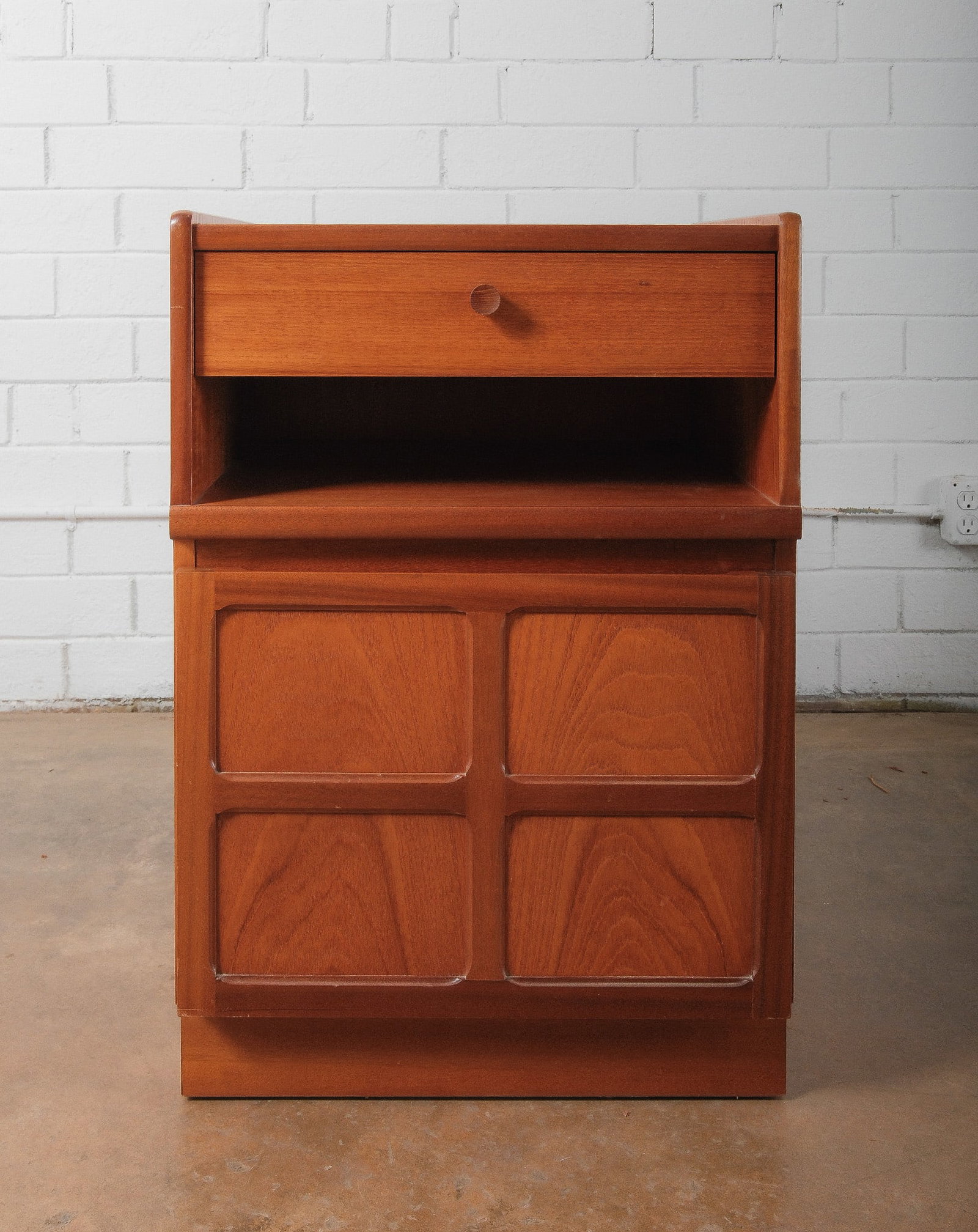 Mid-Century Modern Two Drawer Cabinet with Lower Doors: A petite mid-century modern cabient featuring two upper drawers over a double-door lower cabinet. Constructed in warm toned wood veneer with recessed panel details and simple round door pulls. Compact