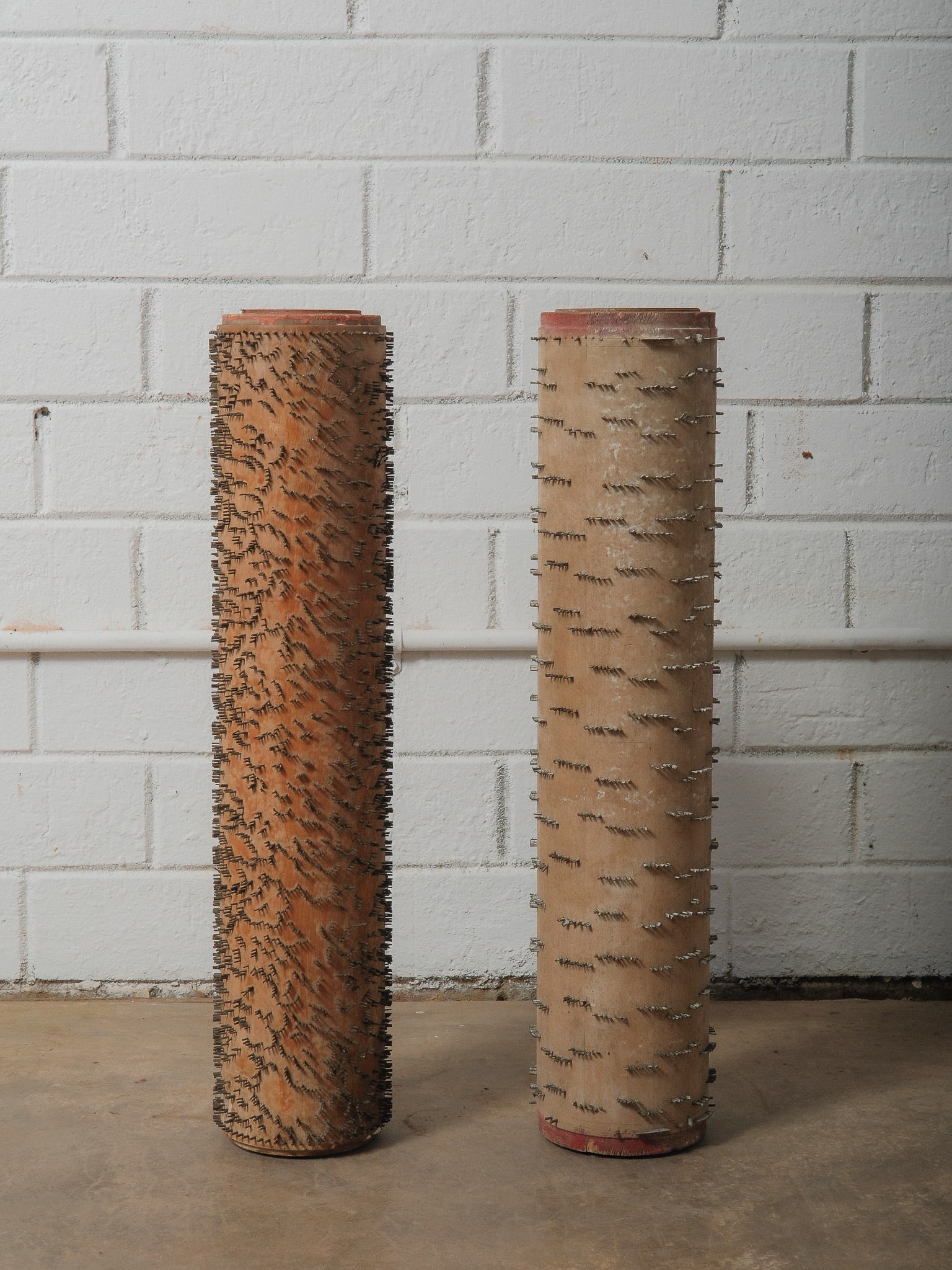 Set of 2 Vintage Wood Wallpaper Carding Rolls: Set of 2 vintage wood wallpaper carding rolls, once used in textile mills for making wallpaper. Each cylindrical drum is densely lined with staggered rows of embedded metal carding teeth, creating a s