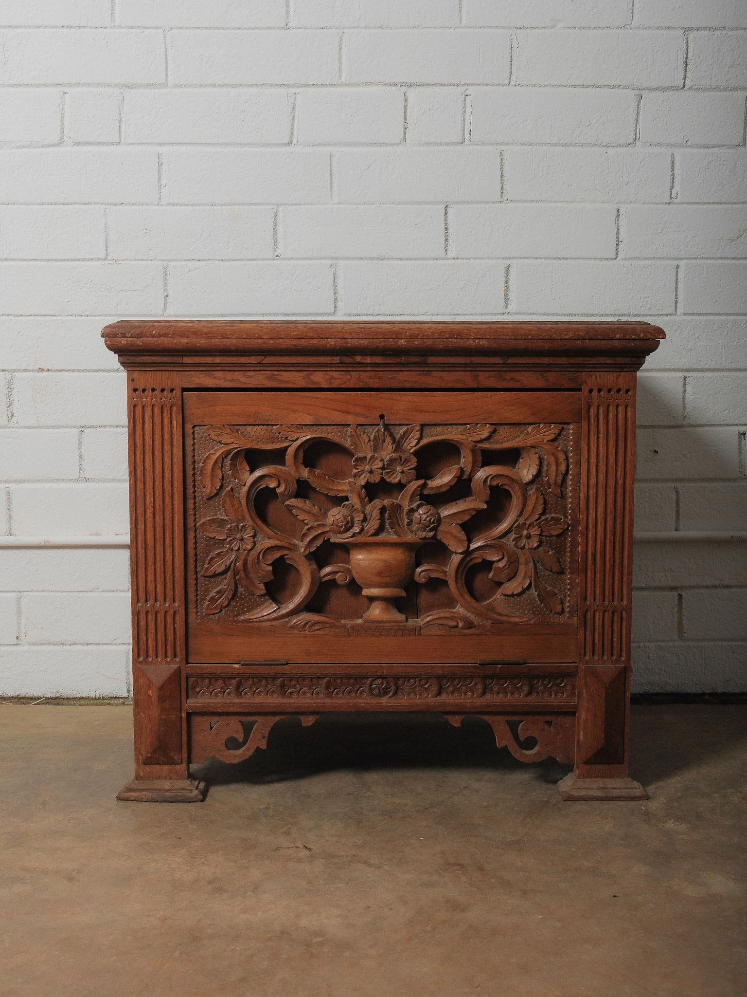 Carved Front Coffer: An ornately carved front coffer in the Renaissance Revival style, boasting dramatic high-relief floral, leaf, and scrollwork carvings, highlighted by a central vase motif. This elegant piece also feat