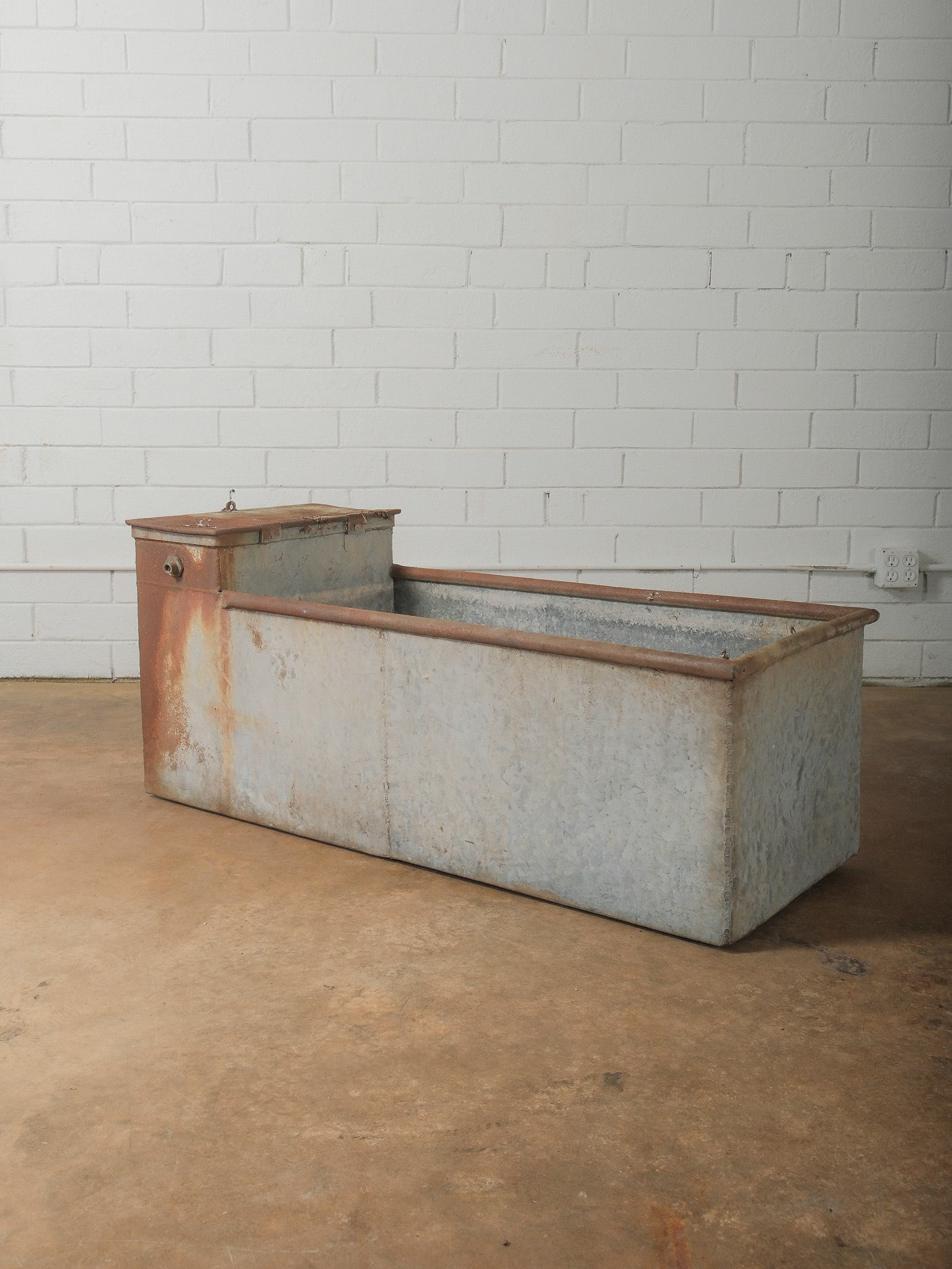 Antique Galvanized Livestock Water Trough: Vintage galvanized metal livestock water trough featuring a large rectangular basin with attached reservoir box. The surface shows natural oxidation and rust patina consistent with agricultural use. S