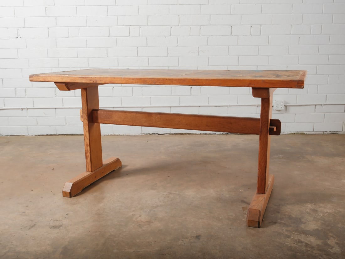Wood Trestle Base Table: Solid wood table featuring plank top and traditional trestle base with stretcher support. Simple utilitarian design suitable as work table or dining table.