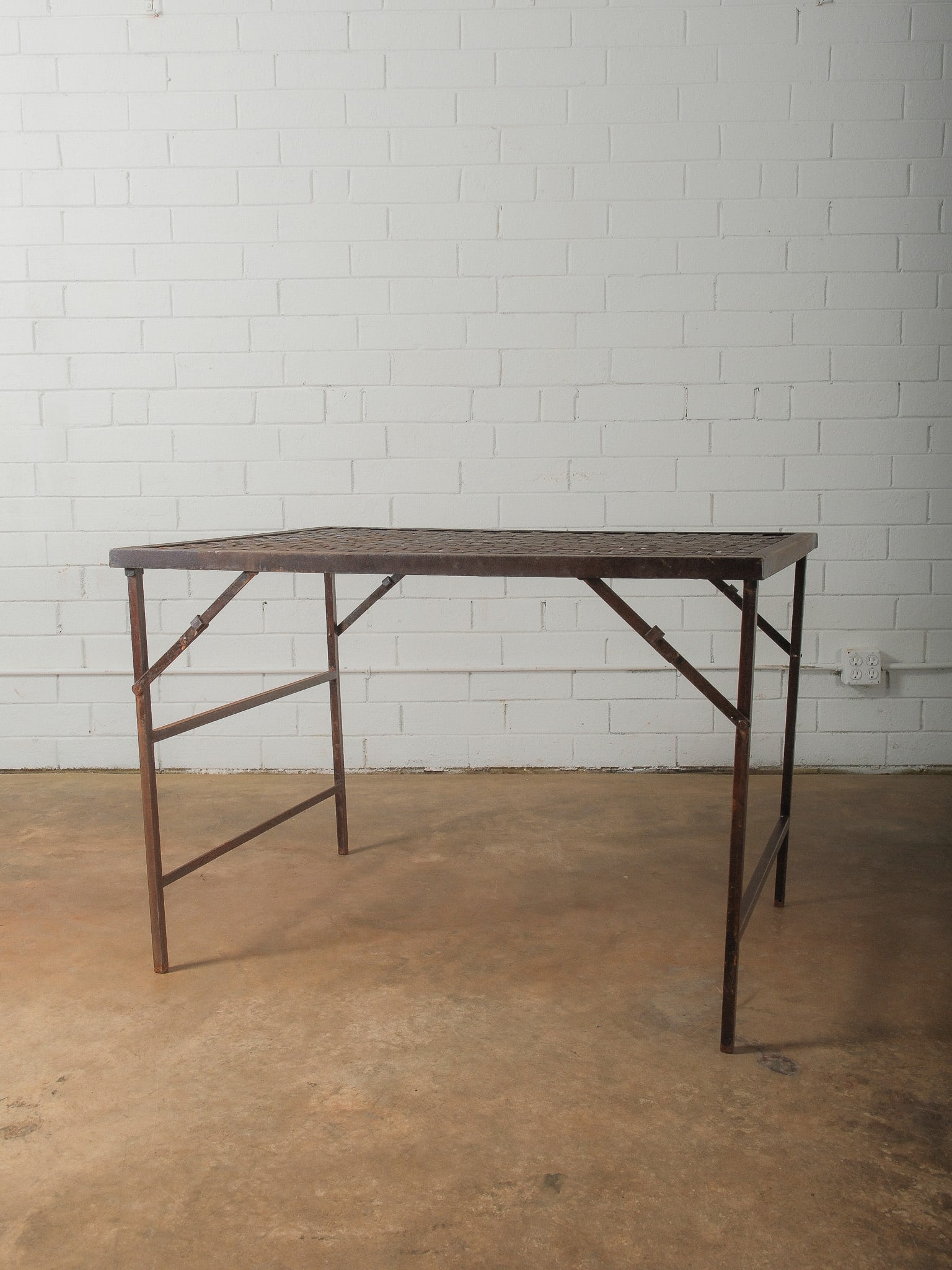 Industrial Folding Metal Work Table: Industrial metal folding table featuring a rectangular frame and perforated lattice-style metal top. The base includes folding supports and cross braces, allowing the table to collapse for storage or