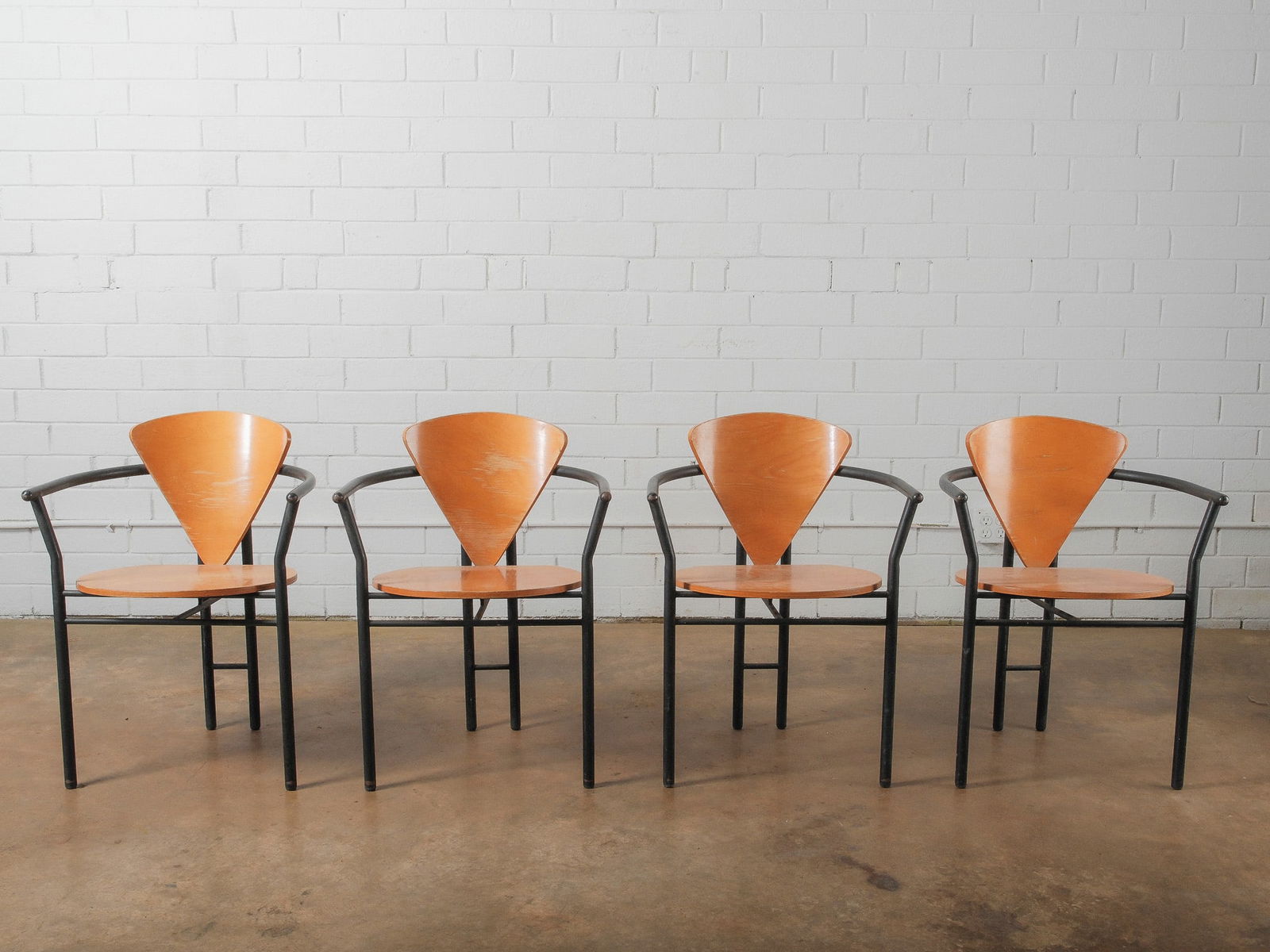 Set of Four Modern Bentwood and Metal Armchairs: Set of four modern armchairs featuring sculptural bentwood triangular backrests and round wooden seats supported by black metal frames. The curved metal arms add visual movement while maintaining a st
