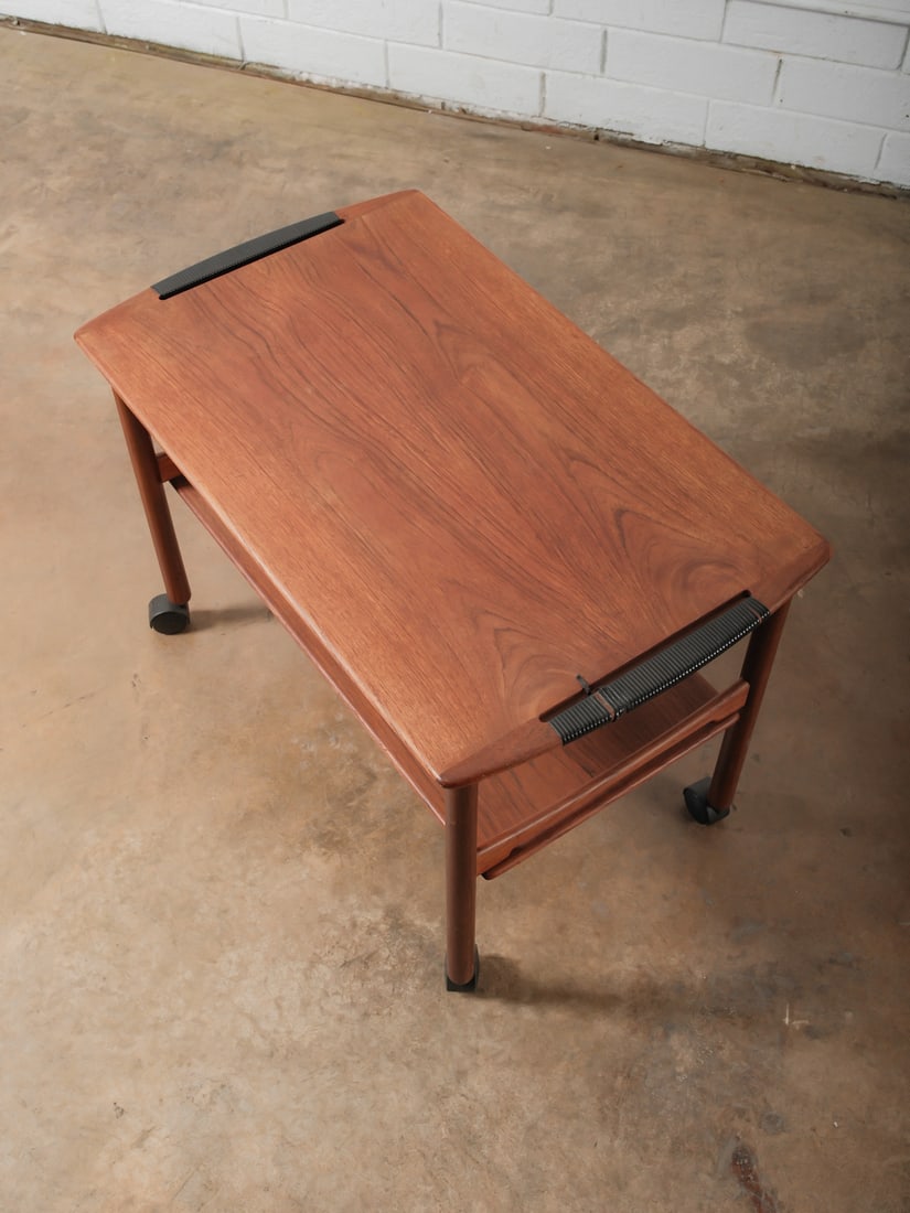 Mid-Century Rolling Bar Cart: Mid-century style bar or serving cart with a warm wood frame, raised edges, and a lower shelf for storage. Mounted on smooth-rolling casters for easy mobility. Functional and stylish, perfect for