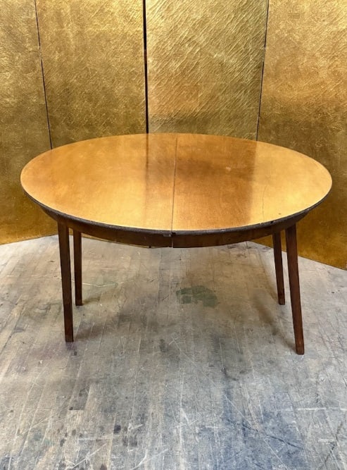 Round Wooden Table with Folding Legs: Round wood table with folding legs and a simple apron. The legs fold inward for storage or transport. The table shows age and wear and would make a great tabletop for a new sturdy base or could be
