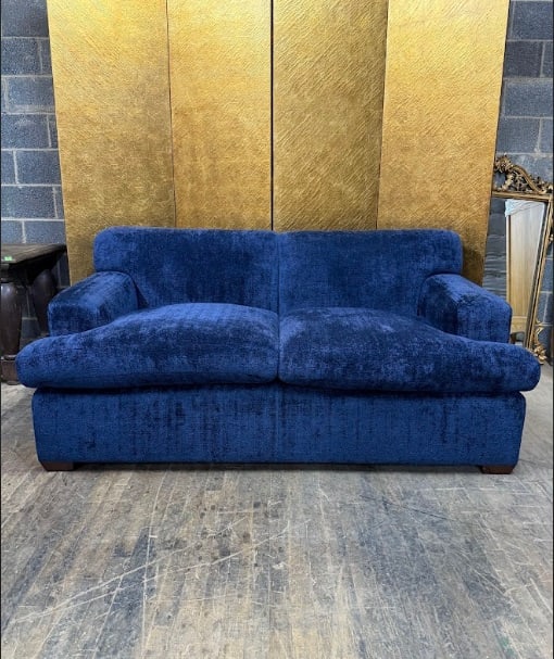 Modern Blue Upholstered Two-Seat Sofa: Contemporary two-seat sofa upholstered in deep blue textured fabric. The piece features wide arms, plush seat cushions, and a simple modern silhouette supported by low wooden feet. The comfortable pro