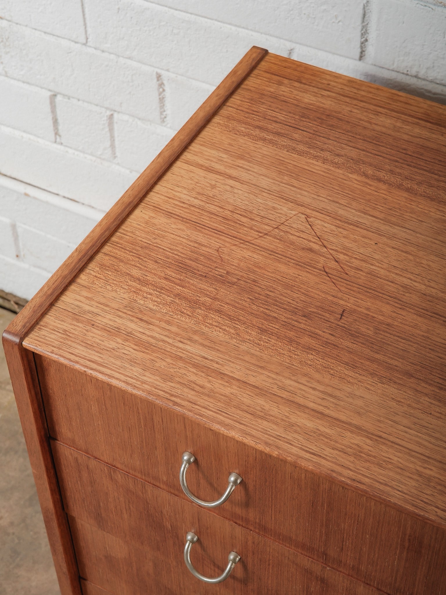MCM Chest for Drawers: This mid-century modern chest features four wide drawers fitted with curved metal pulls. Finished in a warm wood tone. A functional storage piece with classic mid-century proportions, suitable for a b