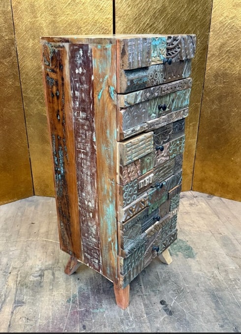 Reclaimed Wood Chest of Drawers: Tall chest of drawers constructed from carved wood panels featuring a patchwork of decorative relief patterns and distressed painted finishes in earthy tones. The stacked drawer fronts display a varie