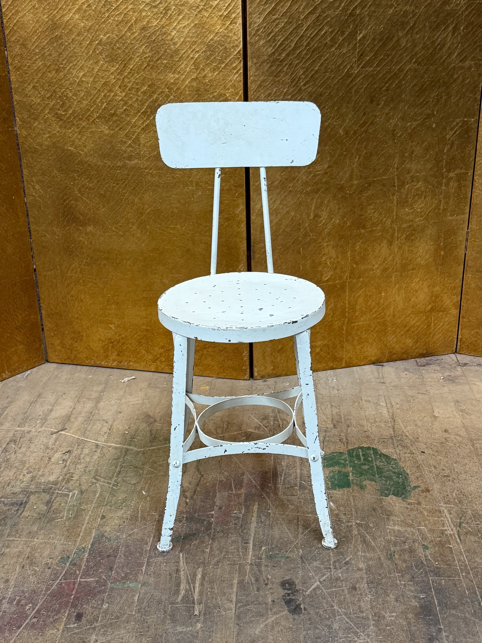 Vintage Painted Stool: Painted metal armless stool featuring a round seat, simple backrest, and decorative circular stretcher support below the seat. Finished in distressed white paint with visible wear consistent with age