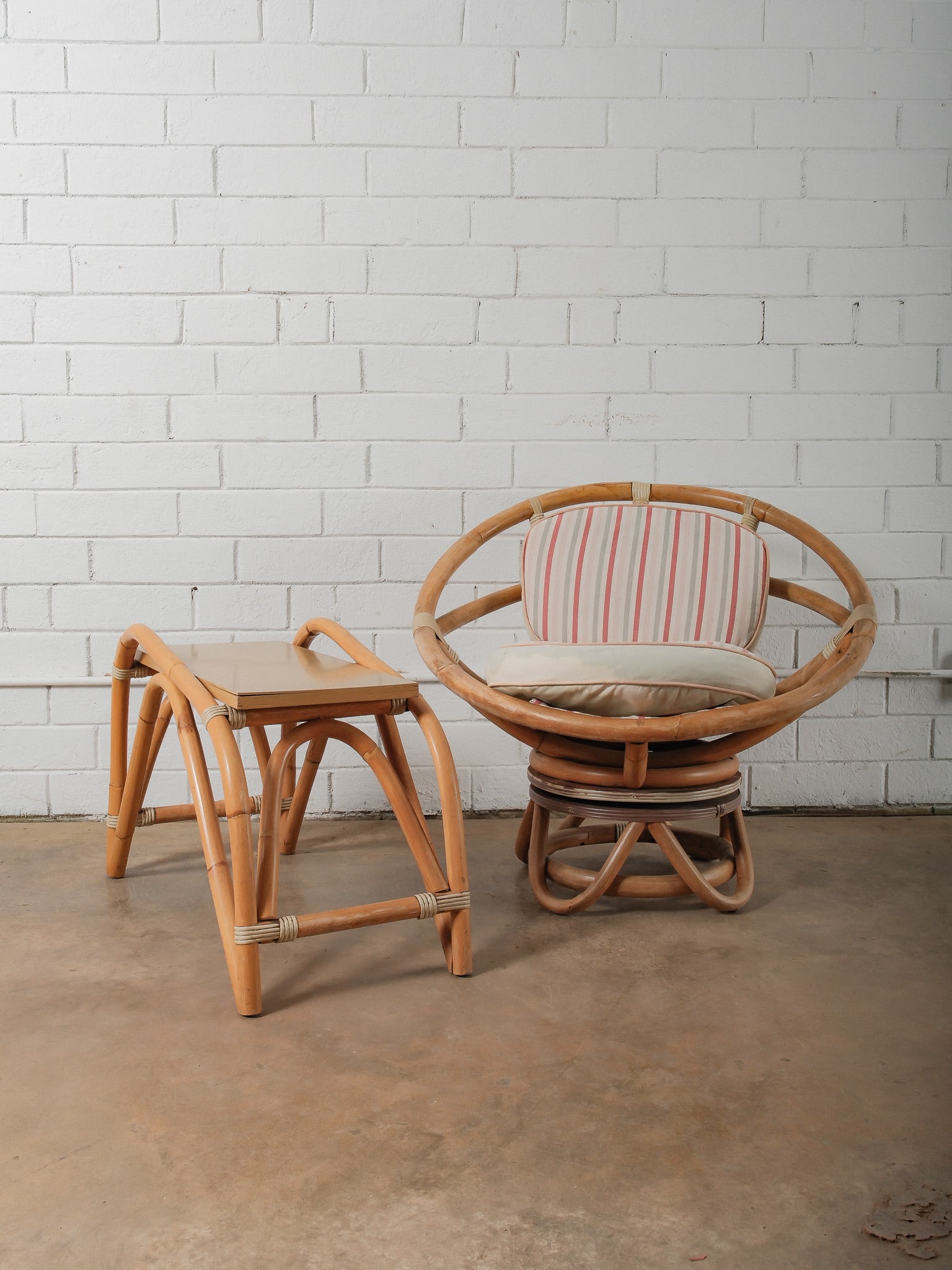 MCM Rattan Papasan Chair and Table: This mid-century chair features a sculptural rattan frame with a rounded design and woven detailing throughout. The chair is fitted with loose seat and back cushions upholstered in a striped fabric. A