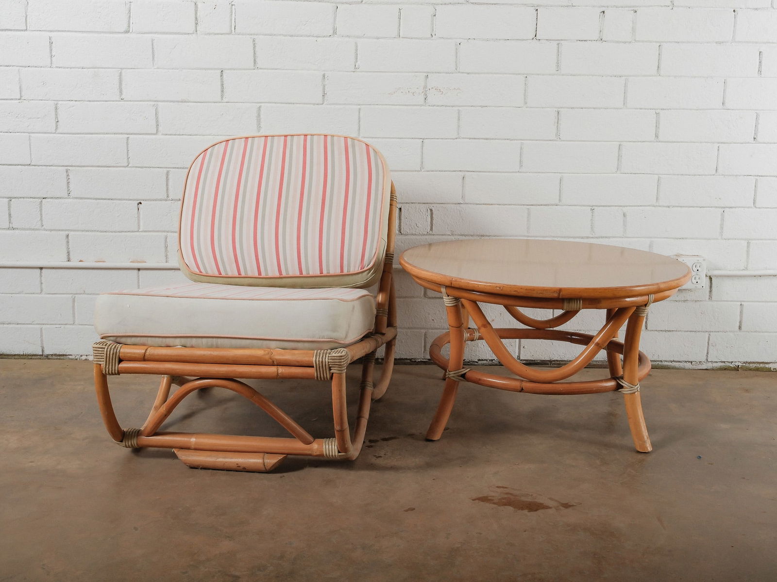 MCM Armless Rattan Chair and Table: This mid-century armless chair showcases a curved rattan frame with woven accents and a rounded backrest. The chair includes loose seat and back cushions upholstered in a striped fabric for added
